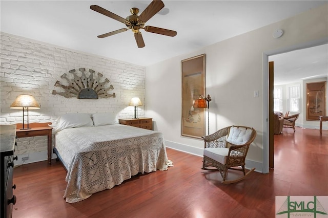 bedroom featuring dark wood-type flooring and brick wall