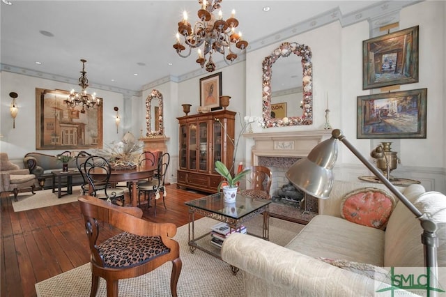 living room featuring ornamental molding, wood-type flooring, a fireplace, and a notable chandelier