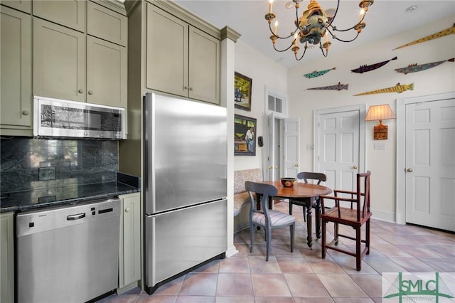 kitchen featuring tasteful backsplash, light tile patterned floors, stainless steel appliances, and an inviting chandelier