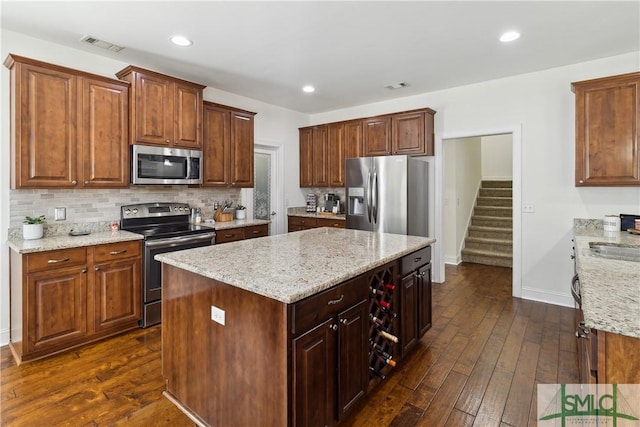 kitchen with backsplash, a kitchen island, dark hardwood / wood-style floors, and appliances with stainless steel finishes