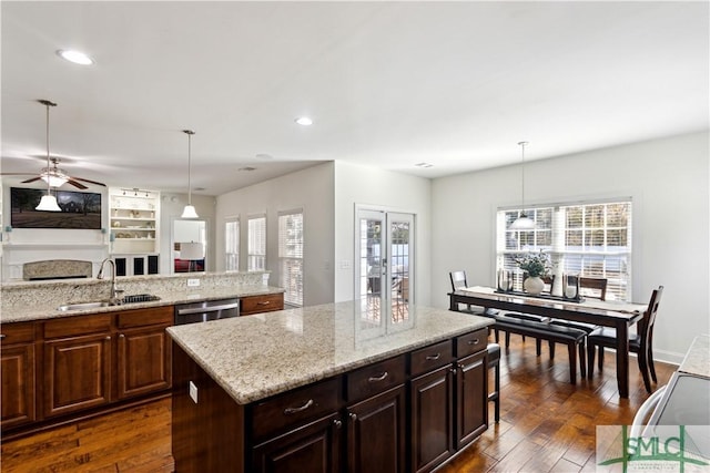 kitchen featuring sink, dishwasher, dark hardwood / wood-style floors, a center island, and decorative light fixtures