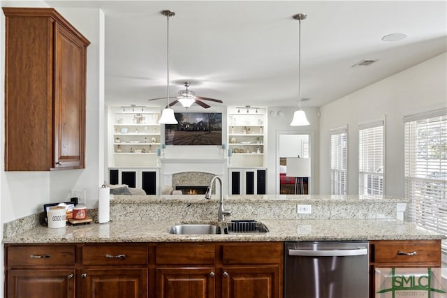 kitchen with light stone countertops, pendant lighting, sink, and stainless steel dishwasher