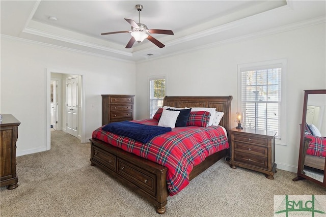 bedroom with a raised ceiling, light colored carpet, and multiple windows