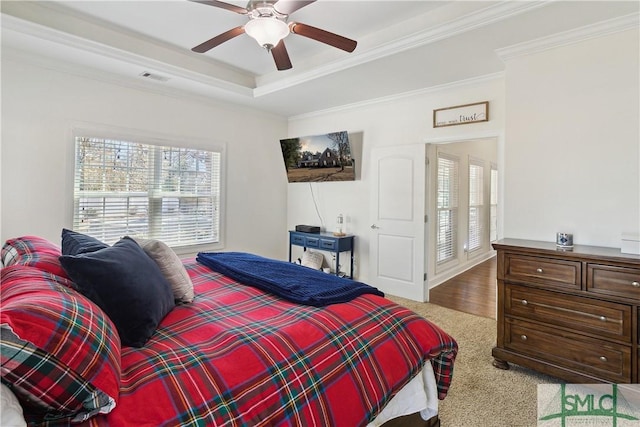 carpeted bedroom with crown molding, ceiling fan, and a raised ceiling