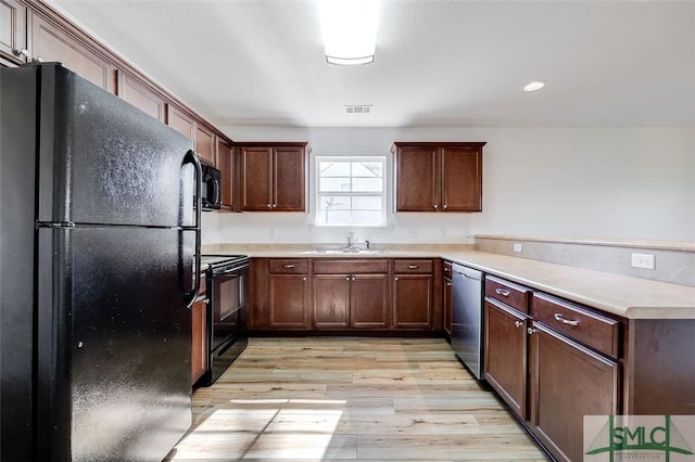 kitchen with sink, black appliances, and light wood-type flooring