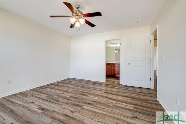 unfurnished bedroom featuring ceiling fan, ensuite bath, and hardwood / wood-style floors