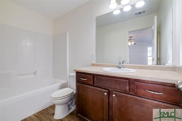 full bathroom featuring  shower combination, ceiling fan, vanity, wood-type flooring, and toilet