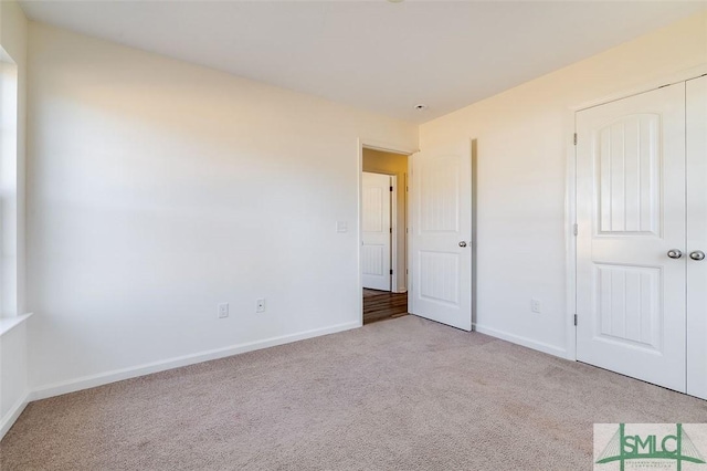 unfurnished bedroom featuring light carpet and a closet