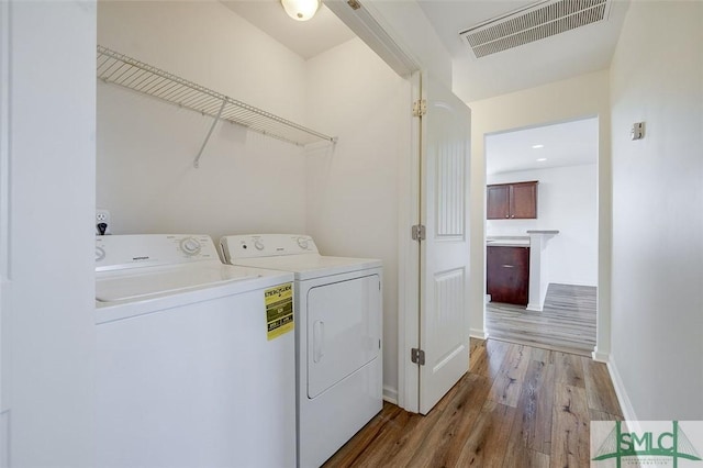 laundry room featuring washer and clothes dryer and light hardwood / wood-style floors