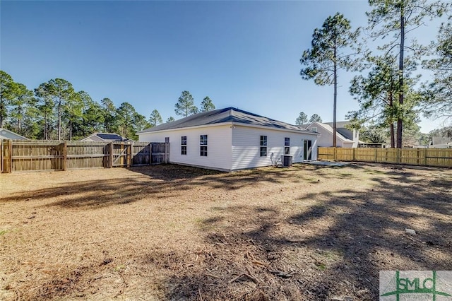 rear view of house featuring central AC and a yard