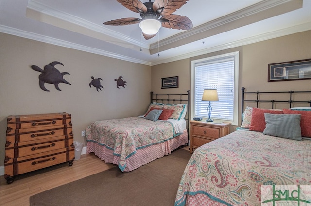 bedroom with ornamental molding, a tray ceiling, and hardwood / wood-style floors