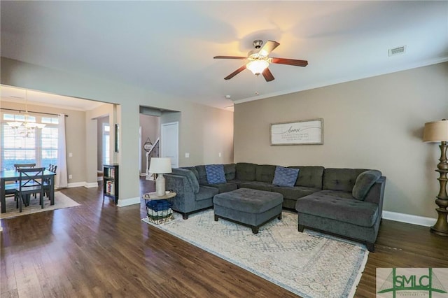 living room with ornamental molding, dark hardwood / wood-style floors, and ceiling fan with notable chandelier