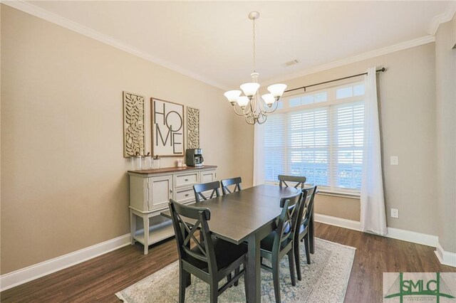 dining room featuring dark wood-type flooring, ornamental molding, and an inviting chandelier