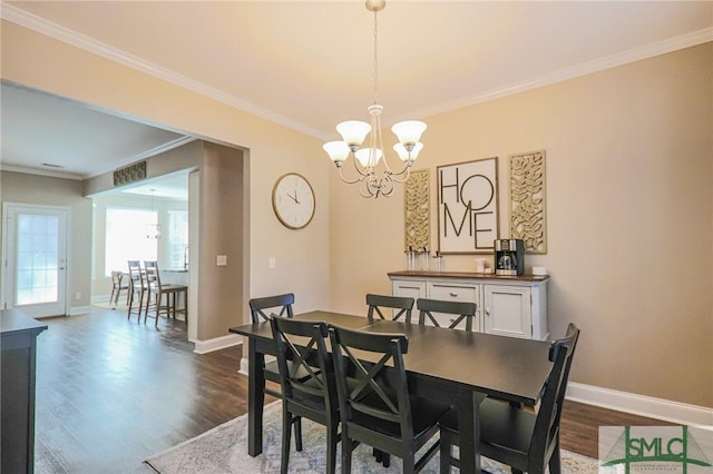 dining space featuring dark hardwood / wood-style flooring, ornamental molding, and an inviting chandelier