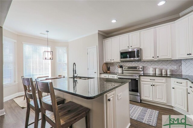 kitchen with appliances with stainless steel finishes, sink, a center island with sink, and white cabinets