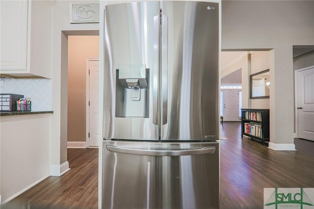 kitchen featuring stainless steel refrigerator with ice dispenser, white cabinetry, dark stone countertops, dark hardwood / wood-style floors, and decorative backsplash