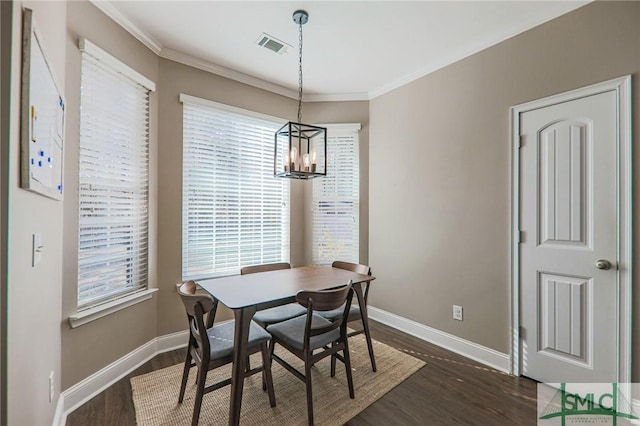 dining room with crown molding, dark hardwood / wood-style floors, and an inviting chandelier