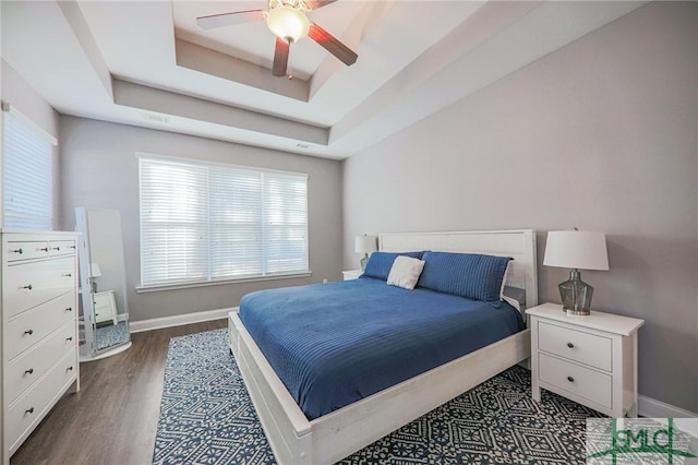 bedroom featuring dark hardwood / wood-style floors, a raised ceiling, and ceiling fan