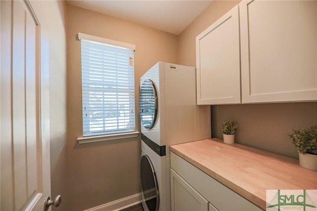 clothes washing area with cabinets and stacked washing maching and dryer