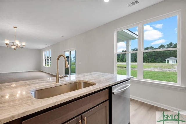 kitchen with a sink, visible vents, stainless steel dishwasher, light stone countertops, and decorative light fixtures