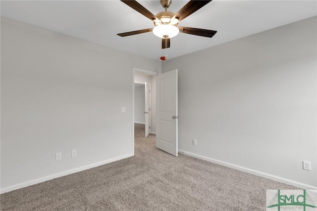 spare room featuring light carpet, ceiling fan, and baseboards