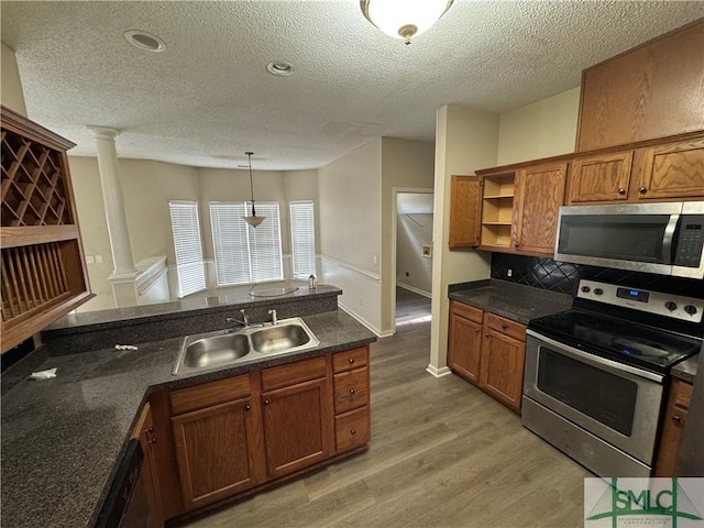 kitchen featuring ornate columns, hardwood / wood-style floors, pendant lighting, sink, and stainless steel appliances