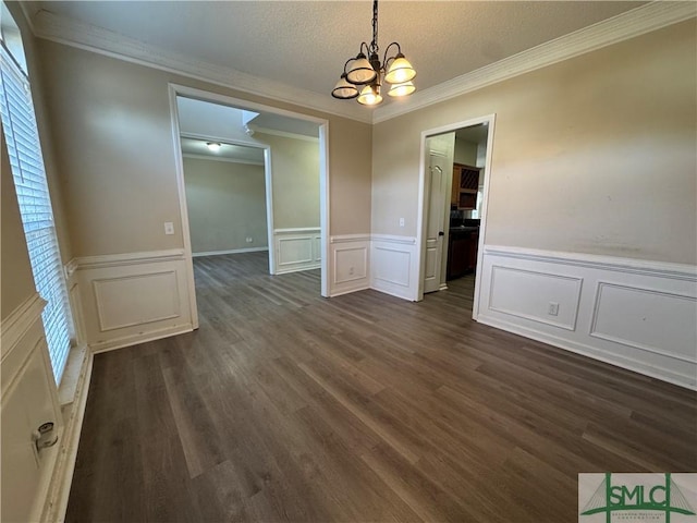 unfurnished dining area featuring dark hardwood / wood-style flooring, crown molding, a textured ceiling, and a chandelier