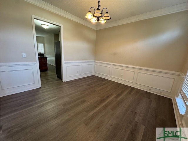 unfurnished room with an inviting chandelier, ornamental molding, and dark hardwood / wood-style flooring