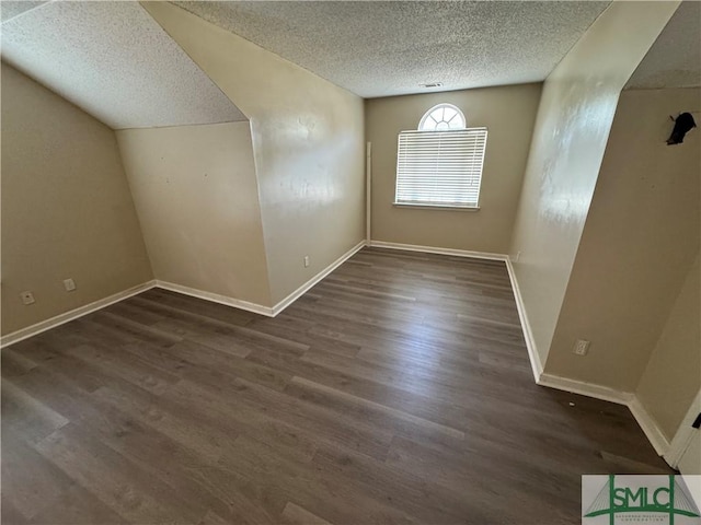 additional living space with dark hardwood / wood-style floors and a textured ceiling