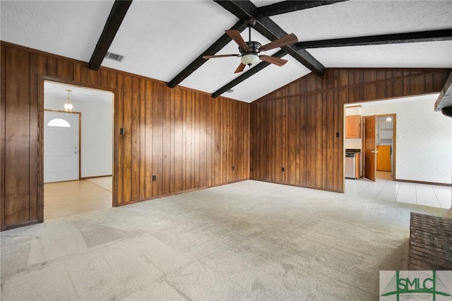 unfurnished living room with ceiling fan, vaulted ceiling with beams, a textured ceiling, light colored carpet, and wood walls