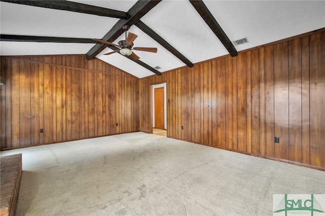 carpeted empty room featuring vaulted ceiling with beams, ceiling fan, and wood walls