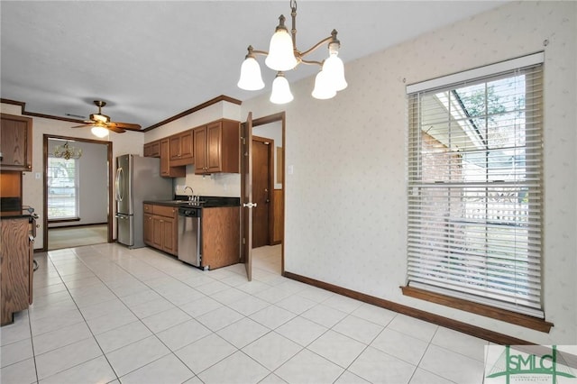 kitchen with stainless steel appliances, ceiling fan with notable chandelier, pendant lighting, and light tile patterned floors