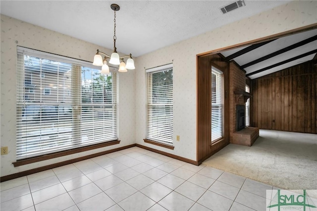 unfurnished dining area featuring vaulted ceiling with beams, a chandelier, light carpet, a textured ceiling, and a brick fireplace