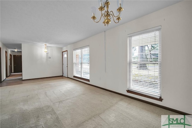 carpeted spare room with a notable chandelier