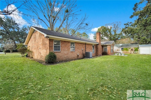 rear view of property featuring central AC unit and a lawn