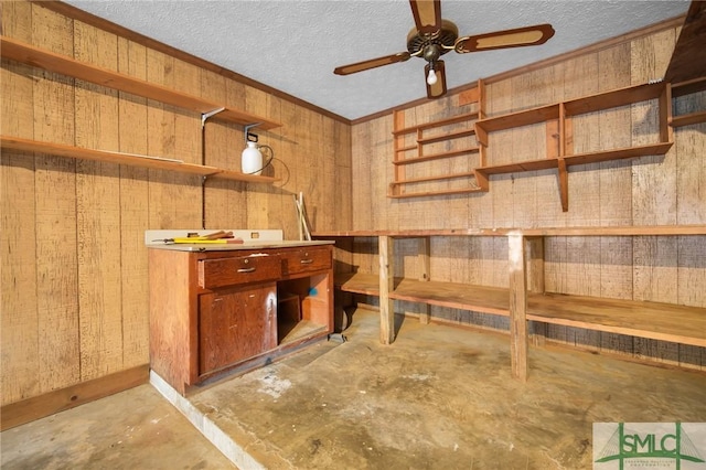 basement featuring ceiling fan, wooden walls, ornamental molding, and a textured ceiling