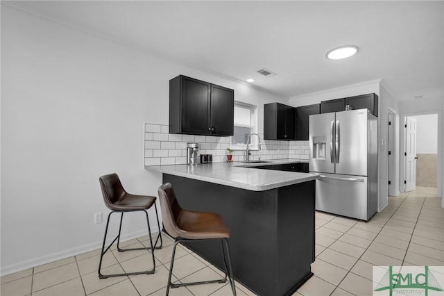 kitchen with stainless steel refrigerator with ice dispenser, a kitchen bar, tasteful backsplash, light tile patterned floors, and kitchen peninsula