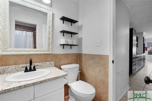 bathroom with vanity, tile walls, tile patterned floors, and toilet