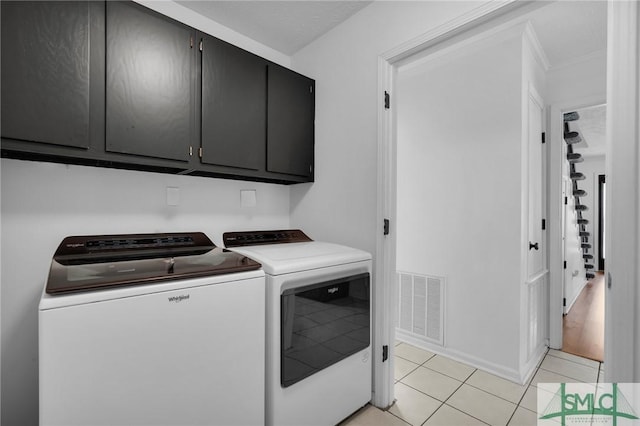 washroom with cabinets, light tile patterned floors, and washing machine and clothes dryer