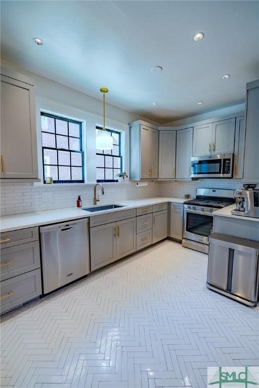 kitchen featuring sink, gray cabinets, stainless steel appliances, and hanging light fixtures