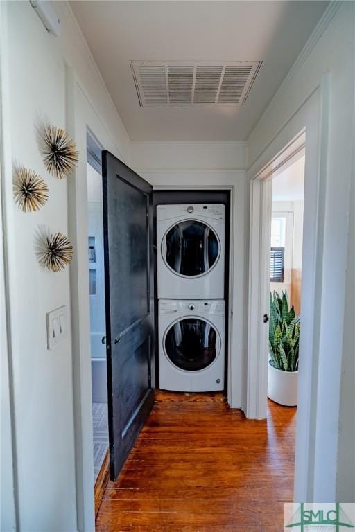 clothes washing area featuring hardwood / wood-style flooring and stacked washer and clothes dryer