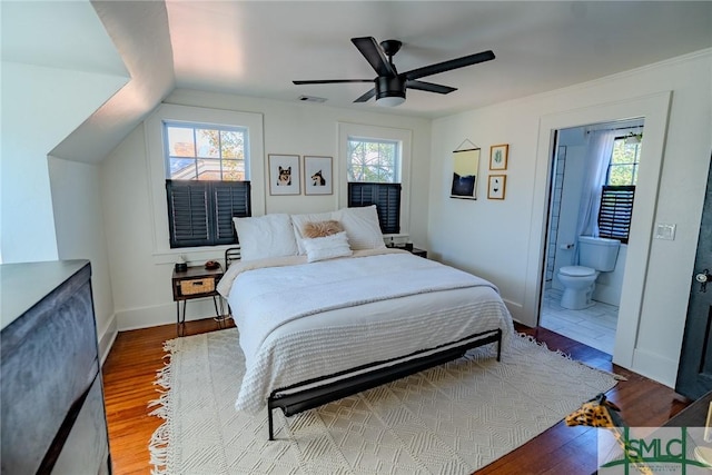 bedroom with ceiling fan, lofted ceiling, ensuite bathroom, and hardwood / wood-style floors