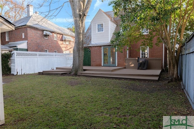 rear view of house featuring a lawn, french doors, and a deck