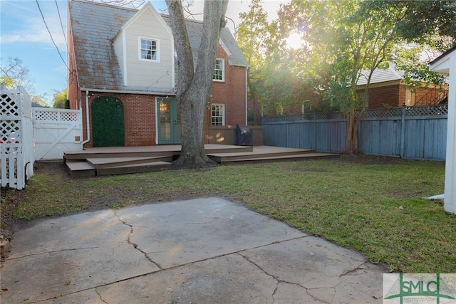 rear view of property featuring a lawn, a patio, and a deck