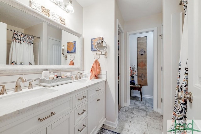 bathroom featuring double vanity, baseboards, a sink, and tile patterned floors