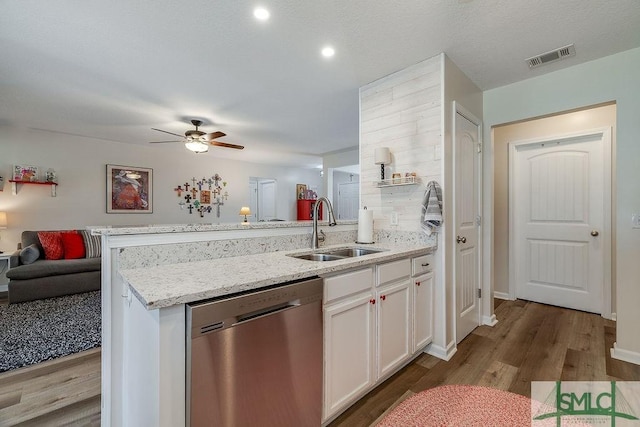 kitchen featuring visible vents, white cabinets, dishwasher, a peninsula, and a sink