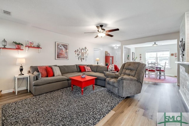 living area with baseboards, ceiling fan, visible vents, and wood finished floors