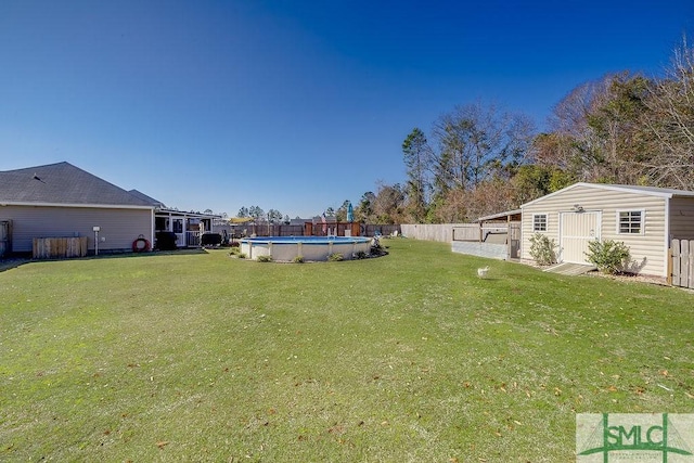 view of yard featuring an outbuilding, a storage unit, fence, and a fenced in pool