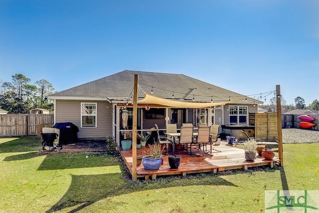 back of house with a yard, roof with shingles, fence, and a wooden deck