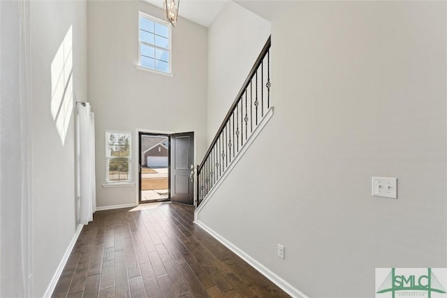 entrance foyer with dark hardwood / wood-style floors, an inviting chandelier, and a towering ceiling